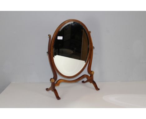 A George III style mahogany oval skeleton toilet mirror, the bevelled mirror plate between slender shaped supports with ring-