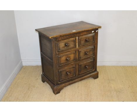 A reproduction oak chest of three drawers, the rectangular top above three drawers, panelled to simulate six drawers, raised 