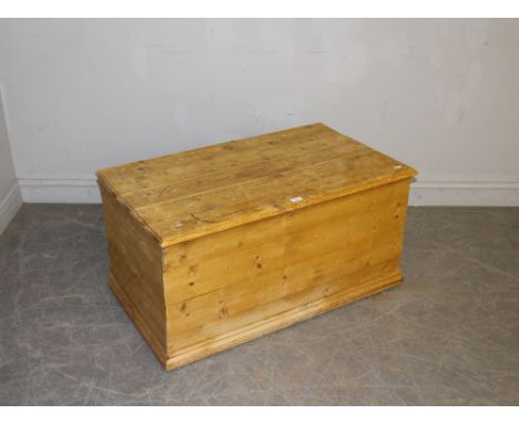 A pine trunk/bedding box, of rectangular form with hinged top, the moulded base with casters 48cm x 95cm x 56cm marks through