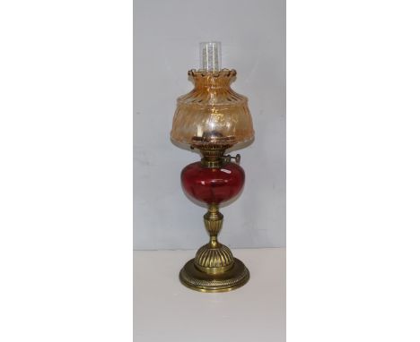 A 20th century 'Duplex' brass oil lamp with, tinted shade, twin adjusters over a cranberry glass reservoir and fluted column,