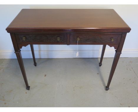 An Edwardian side / card table with 2 frieze drawers faced with blind fretwork brass knob handles, tapering legs and spade fe