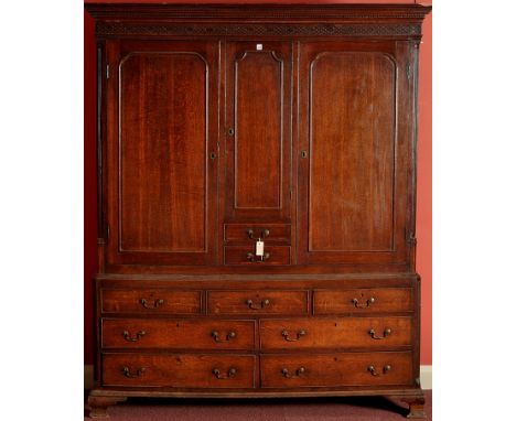 An 18th Century oak cupboard on chest, the flowered Greek key cornice above blind fret work frieze, central covered door encl