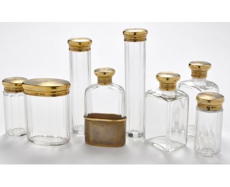 Eight George V silver gilt and glass dressing table jars/flask, by Asprey & Co. Ltd., London 1920, faceted glass bodies, with