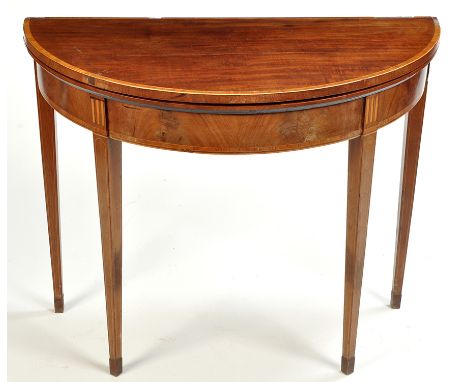 A George III mahogany demi lune turnover top card table, decorated with crossbanding and stringing, raised on square tapering