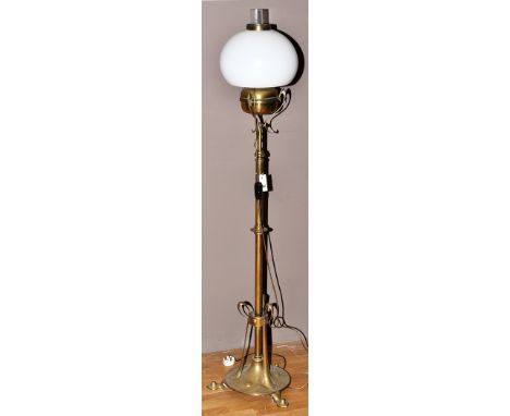 An art nouveau brass standard standard lamp converted to electricity, the brass reservoir fitted associated shade, tapering s