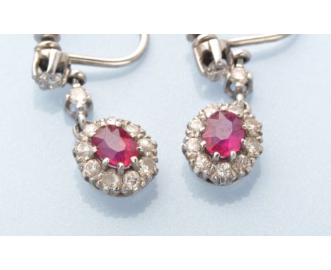 A pair of ruby and diamond cluster drop earrings, each oval facet cut ruby surrounded by nine brilliant cut diamonds held fro