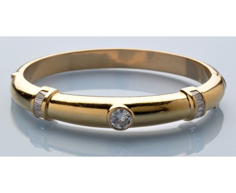 A diamond and 18ct. yellow gold bangle, the central brilliant cut diamond measuring approximately 1.00 carats flanked by shou