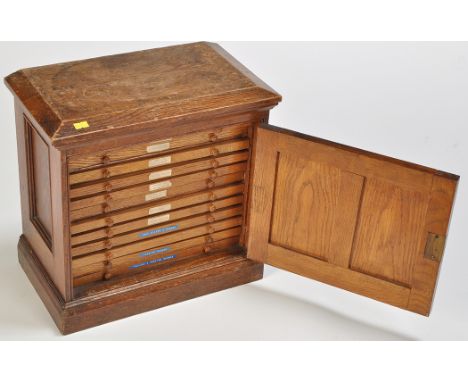 A 19th Century oak specimen coin cabinet, the bevelled top above panel door opening to reveal twelve drawers each with turned