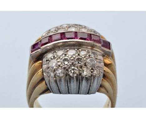 A ruby and diamond dress ring, set with a central row of seven square facet cut rubies in channel mount, graduated brilliant 