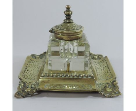 An ornate Victorian pierced brass inkstand, with a cut glass inkwell, on a scrolled square base, stamped no.2734/2, 18cm wide