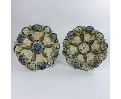A near pair of 19th century Castle Hedingham pottery dishes, each decorated in relief with various latin masks, divided by va