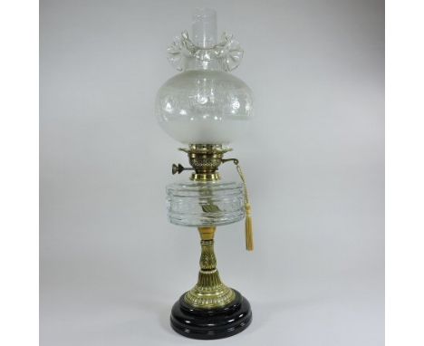 A late 19th century brass oil lamp, with a facet cut clear glass reservoir and etched glass shade, 62cm tall