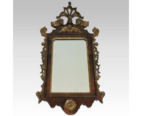 An ornate George II style rosewood and parcel gilt framed fret carved wall mirror, the rectangular bevelled glass having a gi