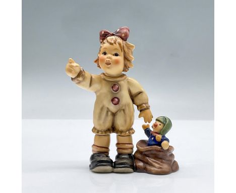 This charming figurine features a girl adorned with a red polka dot bow, her arm gracefully extended as she points excitedly 