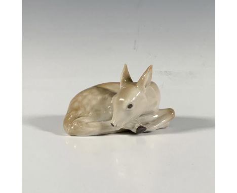 Adorable glazed porcelain figure of a baby deer curled up for the night. Depicted in beige with light spotting on the coat. D
