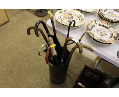 A painted metal stick stand and contents of parasols and walking sticks