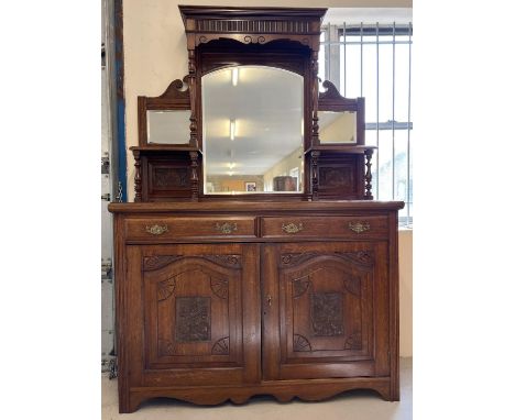 An Edwardian dark oak mirror backed side board with decorative carved columns and panelled detail. Bevel edged glass and deco