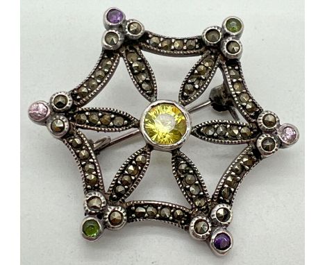 A vintage silver brooch modelled as a star/spiders web, set with round cut coloured stones and marcasite's. Indistinct stamp 