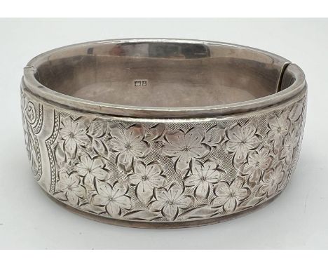 A vintage silver bangle with push clasp and half floral engraved decoration. Silver marks to inside of bangle, hallmarked Bir