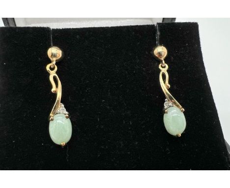 A boxed pair of 9ct gold green jade and diamond drop style earrings, no butterfly backs. Each earring set with an oval caboch