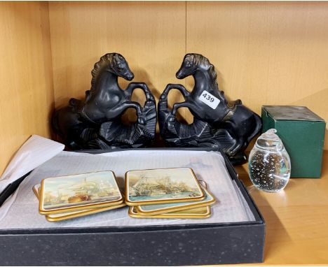 A pair of ceramic horse figures with a set of historic image table mats and a glass paperweight.