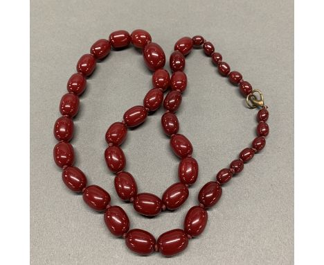 A faux cherry amber necklace, L. 82cm. With a pair of matching earrings.