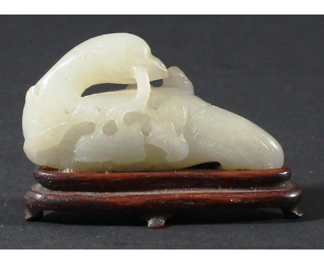 CHINESE WHITE JADE PHOENIX, possibly Ming, carved with it head turned backwards and holding a fruiting peach branch in its be