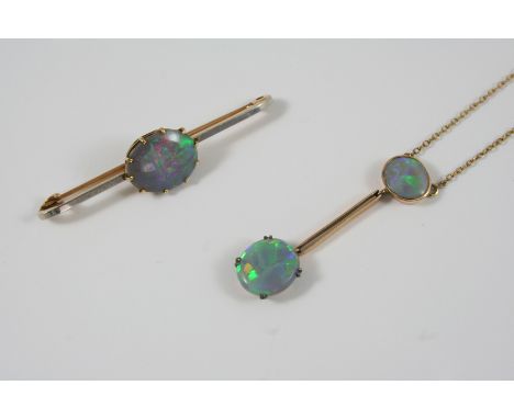 A BLACK OPAL AND GOLD PENDANT formed with two oval-shaped solid black opals in 15ct. gold, on a fine link chain, the pendant 