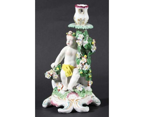 BOW PORCELAIN CANDLESTICK, circa 1760, modelled seated next to floral encrusted branches, on a scrolling base, height 24cm