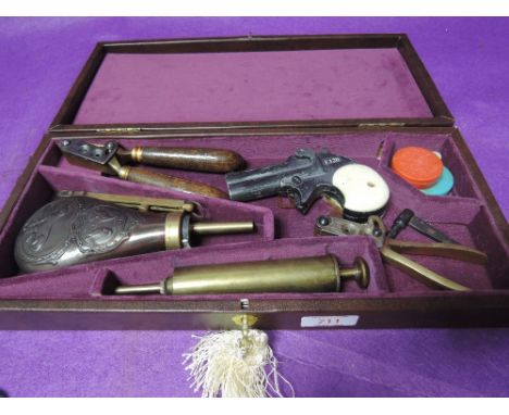 A box containing copy Derringer pistol, bullet moulds, powder flask and grease gun