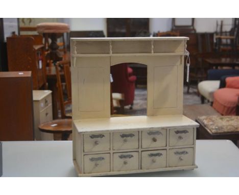 A 19thc treen child's dresser with painted finish in cream, fitted plate rack back and open aperture, fitted two rows of four