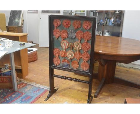 A 19th century glazed double sided  firescreen, possibly rosewood, with sliding panels enclosing a collection of silk ribbon 