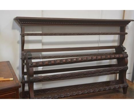 An Edwardian Arts &amp; Crafts carved three tier walnut wall mounted plate rack, with Celtic style snake carving and another,