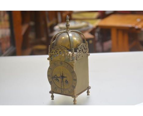 A reproduction 1920s/30s brass lantern style clock with bell and finial surmount, with pierced brass panels to side and engra