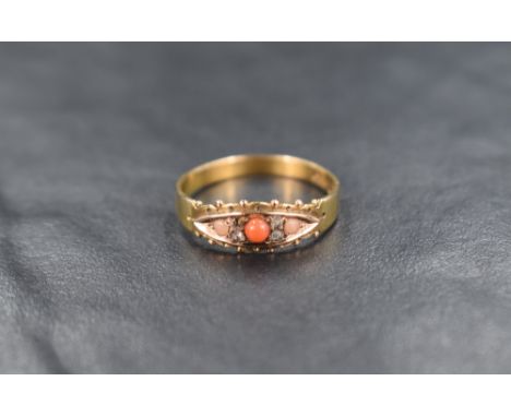 A 15ct gold coral and diamond ring, the central cabochon flanked by diamond chips and two further paler coral cabochons, ring
