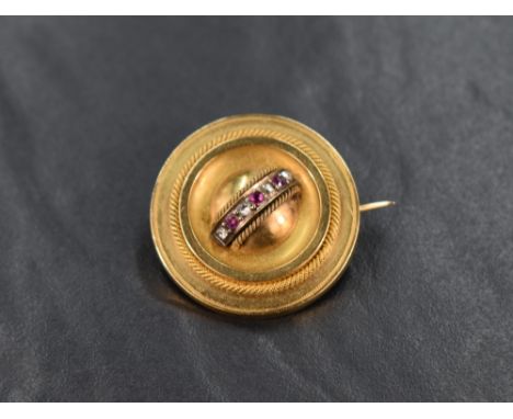 An 18ct gold ruby and diamond brooch, the circular brooch having alternating ruby and diamond chips to the centre with twiste