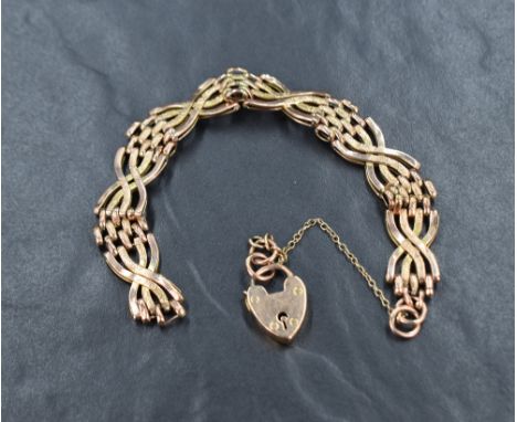A rose metal four bar twist gate bracelet marked 9ct, having a heart padlock and safety chain, 14.6g. Missing links so not we