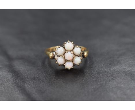 A 9ct gold opal seven stone cluster ring having a low claw set mount with balled shoulders, ring size M/N and approximately 3