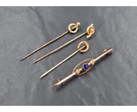 Three yellow metal stick pins, comprising a diamond set knot motif marked 15ct, another of a knot motif marked 15ct and a hor