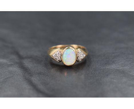 A 9ct gold opal dress ring having a trio of diamond chips to each shoulder on a 9ct gold moulded loop, ring size P and approx
