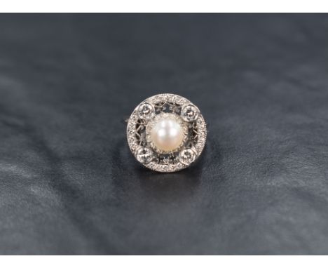 An 18ct white gold pearl and diamond ring having a central cultured pearl within a halo border set with four diamonds and dia