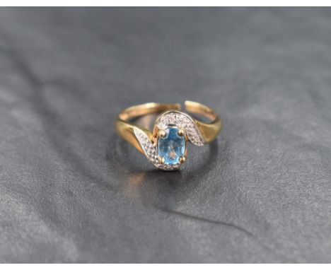 A 9ct gold blue topaz and diamond ring, the central oval cut topaz measuring approximately 0.70, with illusion set diamond ch