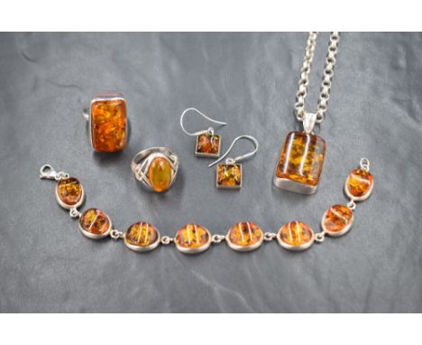 An assortment of silver amber jewellery, comprising a chunky rectangular ring, an oval ring with Celtic inspired shoulders, a
