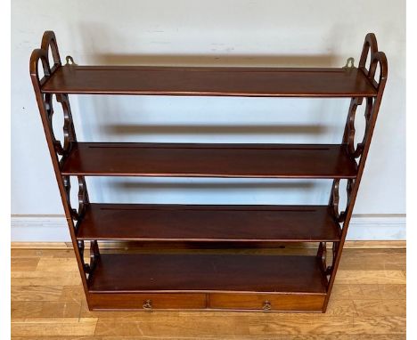 A mahogany wall shelf display unit, having scroll sides, with four shelves, over two frieze drawers with brass drop handles.H