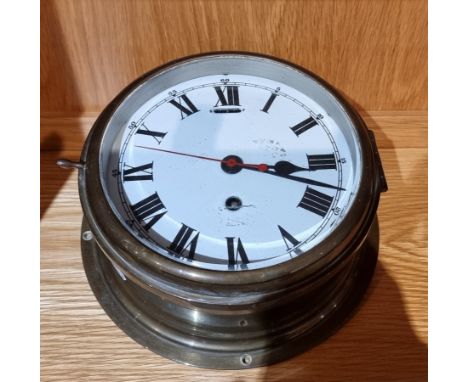 An early 20th century ships bulkhead clock, having brass case with enamelled dial and Roman numerals, housing an 8 day manual