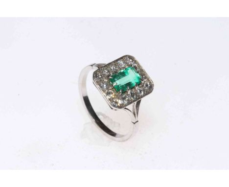 Emerald and diamond platinum ring, the rectangular setting with approximately 0.75 carat emerald bordered with fourteen brill