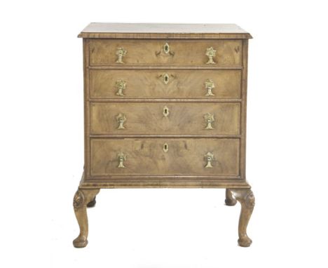 A 1920s walnut chest of four drawers with oak linings, of short proportions, having a book fold veneer top with herringbone i