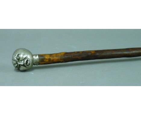 An early 20th century walking stick, the silver plated man's head terminal with an irritating fly, 91cm long