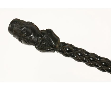 An antique tribal walking stick, with a figural head teminal handle, with geometric and spiral twist sections along the shaft