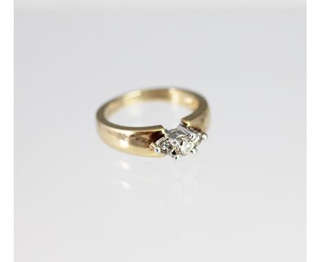 A three stone diamond ring, the three graduated diamonds, each claw set white metal to the broad 9ct yellow gold hoop, weight